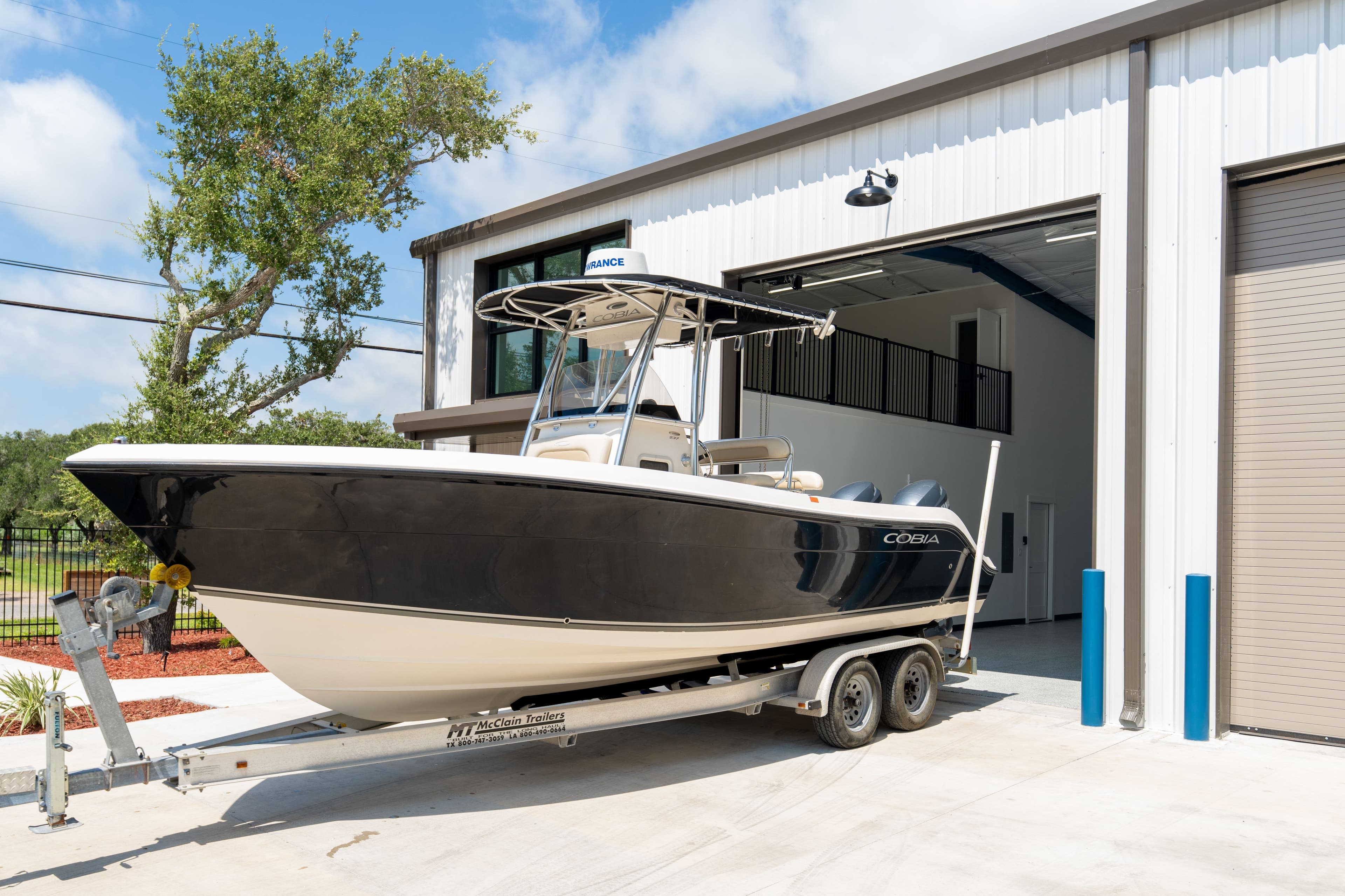 A center-console boat on its trailer at an open garage door