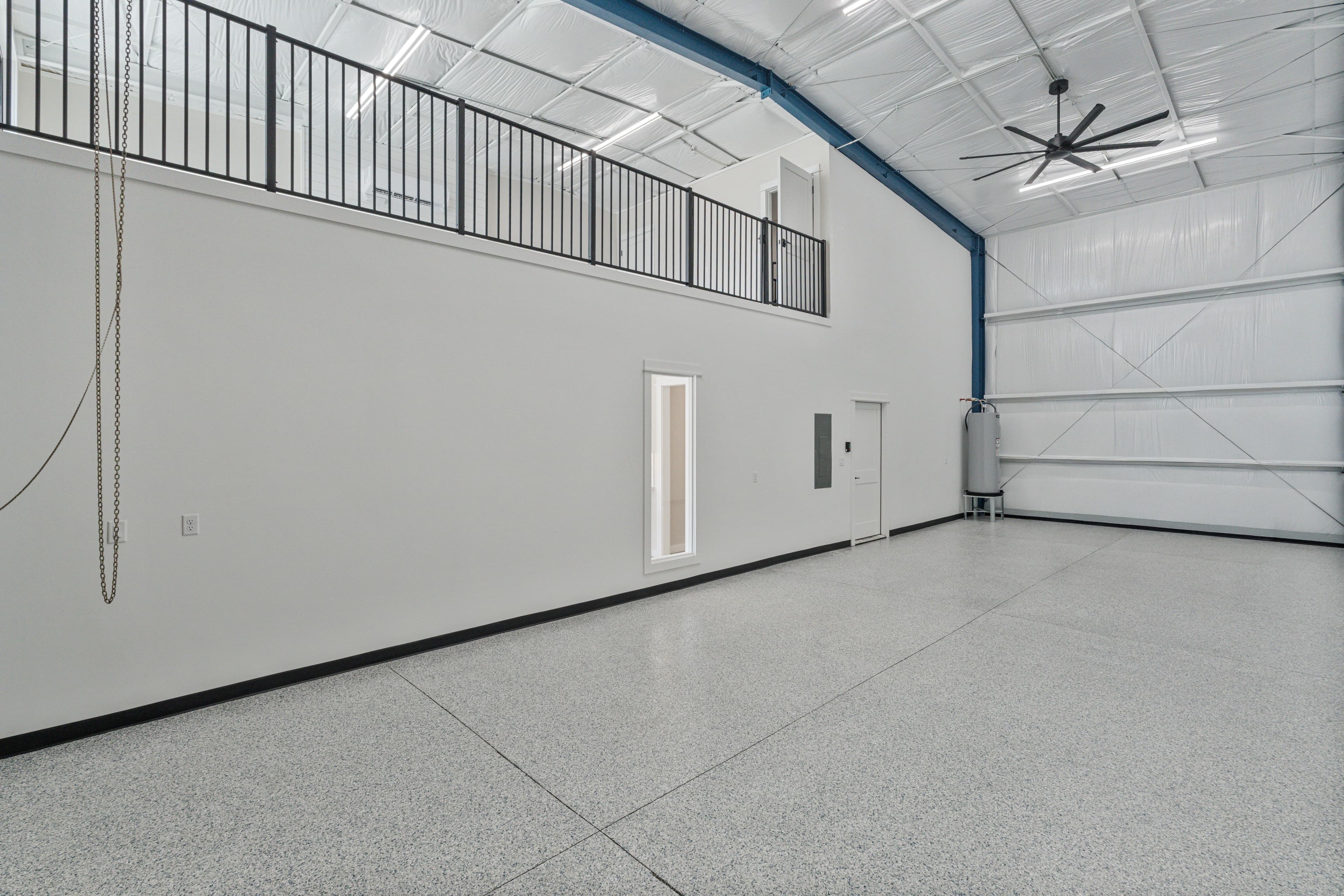 Inside the empty garage: epoxy floor, loft rail above and the roll-up door
