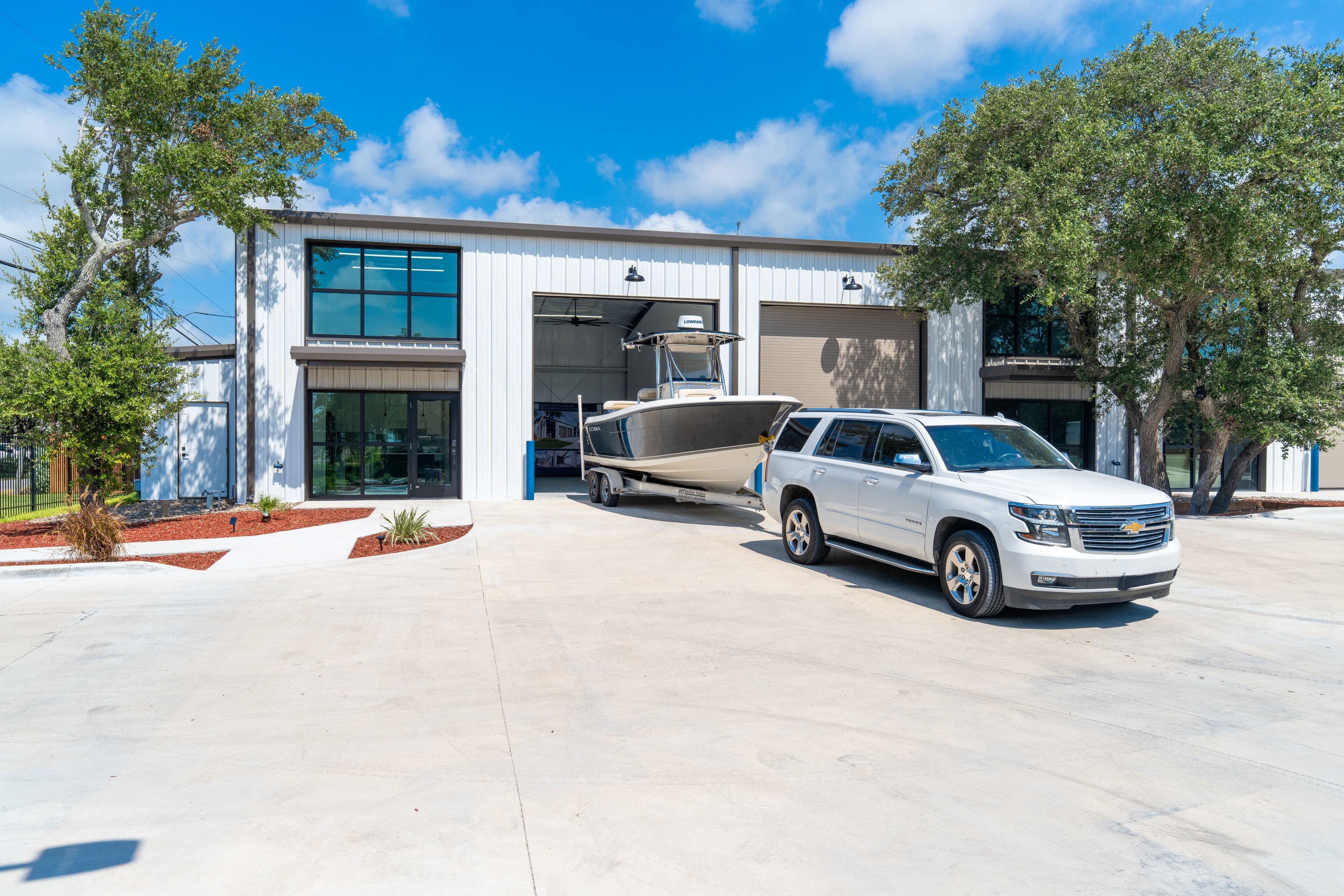 The building in daylight with a boat and SUV parked out front