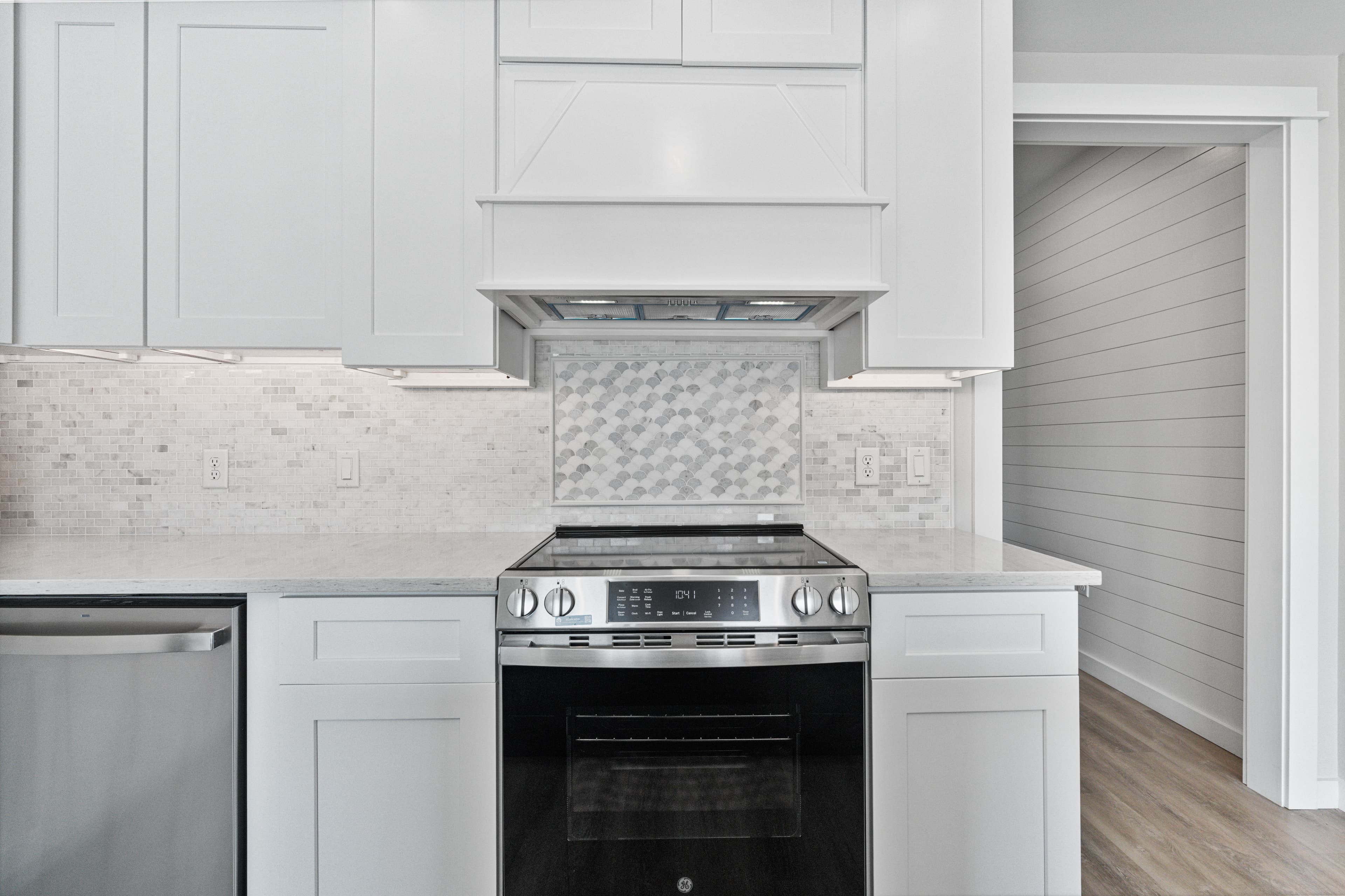 Kitchen range with a tiled backsplash and white cabinets