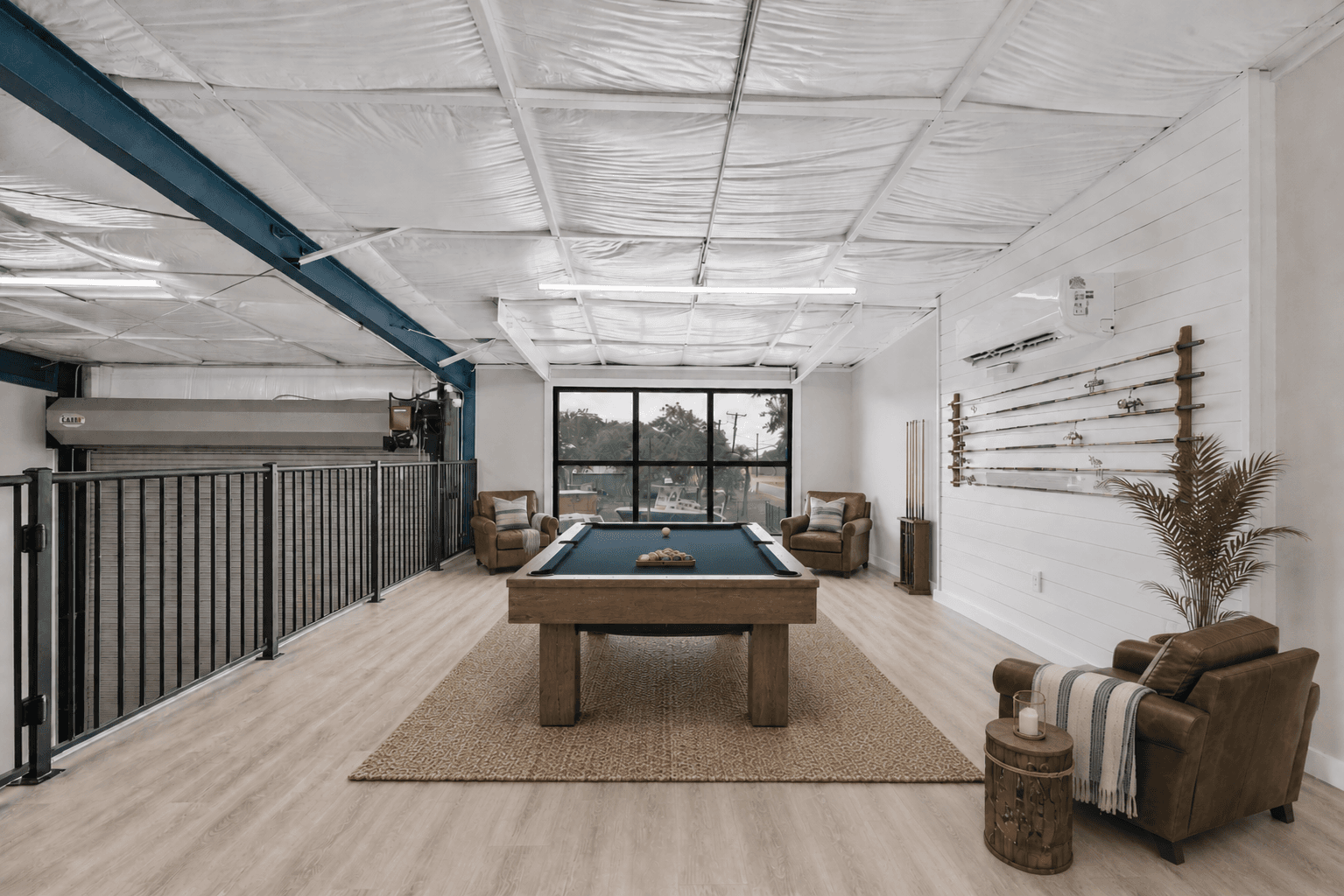 The loft with a pool table, open to the garage below, virtually staged
